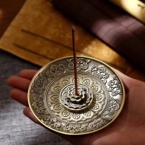 Handcrafted Buddhist incense holder with bronze finish and embossed lotus patterns held in palm, close-up view