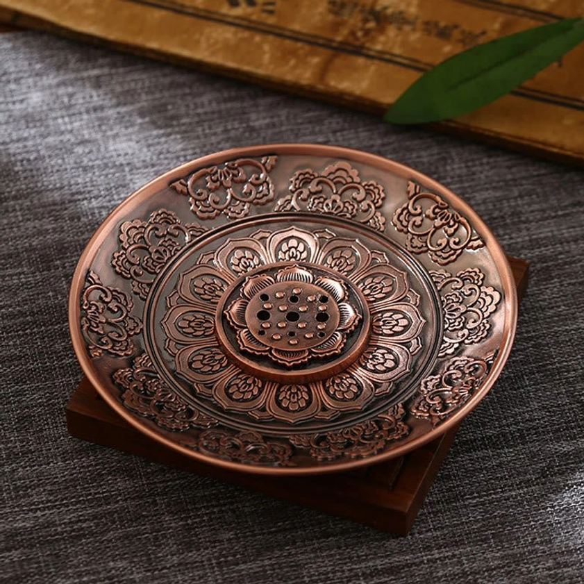 Red copper finish Buddhist incense holder with lotus-shaped incense insert, overhead tabletop view