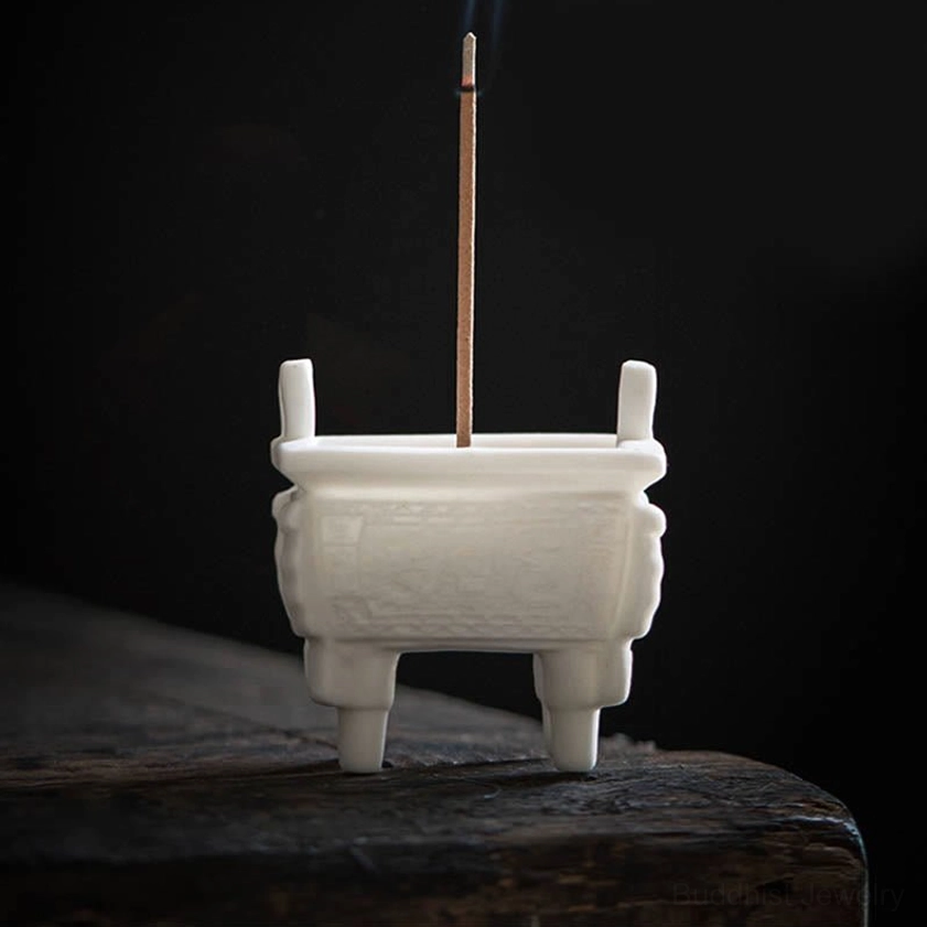 Buddhist ceramic incense burner with side-view close-up showing four support legs, upright lugs, carved patterns, and burning incense