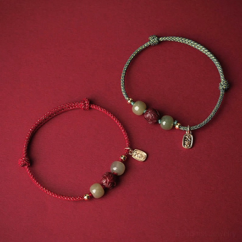Two mixed-color Buddhist luck bracelets with red and green braided strings, Hetian jade beads, cinnabar lotus pendant, and gold accents, flatlay comparison
