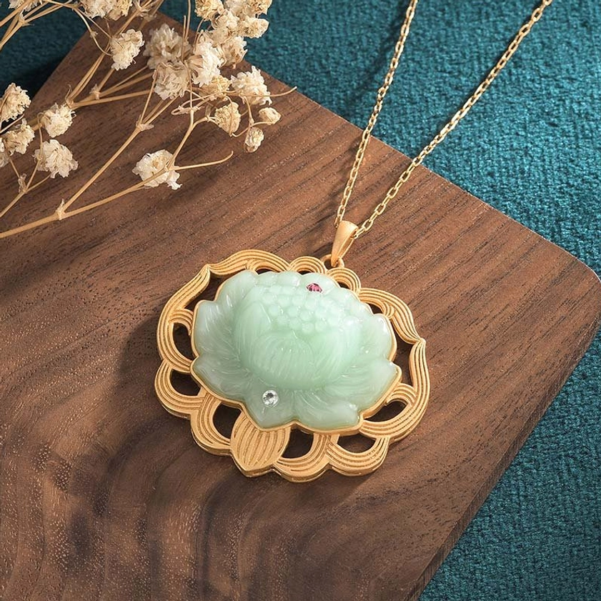 Jade lotus Buddhist necklace pendant - overhead oblique angle displaying ornate gold metal frame texture with red and clear rhinestone decorations, carved jade lotus detail