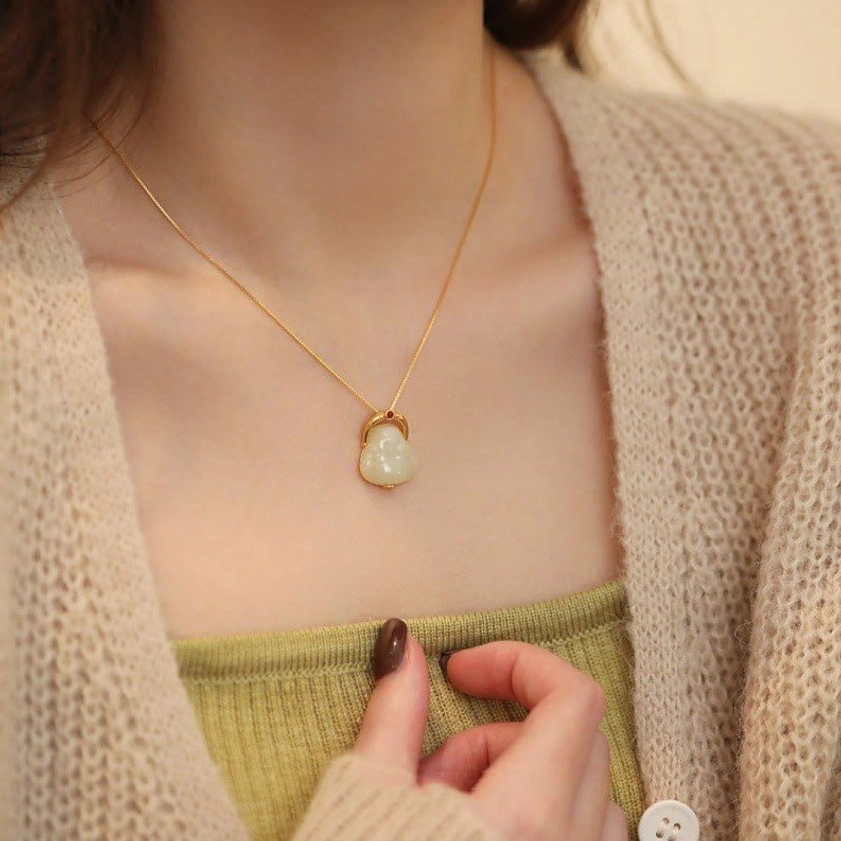 Laughing Buddha sterling silver jade necklace worn on female neckline with knitwear background