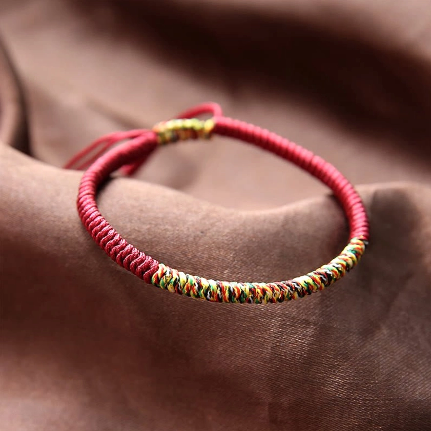 Burgundy Buddhist King Kong Knot braided bracelet with multicolor woven stripe on brown satin background, handmade adjustable rope tail