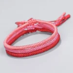 Double-layer ombre red Buddhist king kong knot bracelet with adjustable tassel clasp, showing gradient from light pink to deep red
