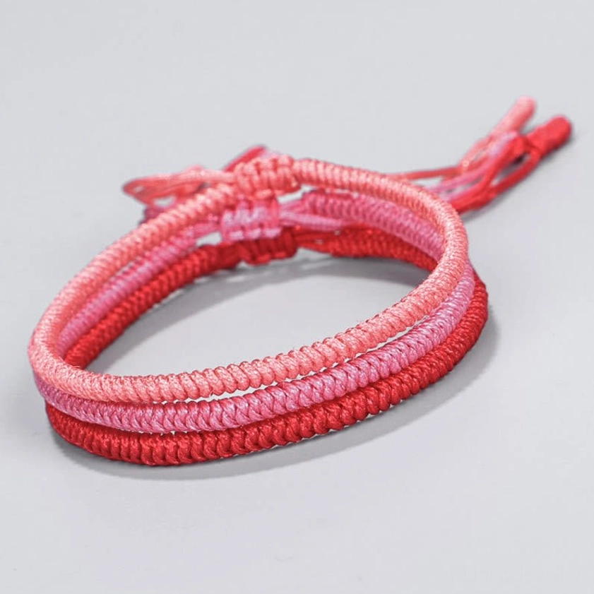 Double-layer ombre red Buddhist king kong knot bracelet with adjustable tassel clasp, showing gradient from light pink to deep red