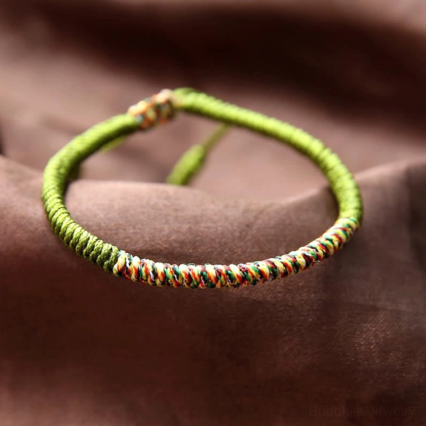 Olive green Buddhist King Kong Knot braided bracelet with mixed-color woven edge detail and hand-woven adjustable rope on brown satin background