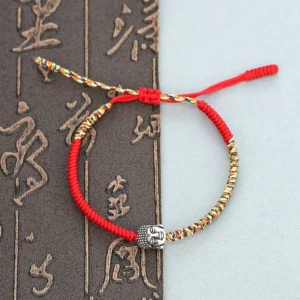 Handmade Buddhist King Kong knot red string bracelet with colorful woven threads and silver Buddha charm on calligraphy background