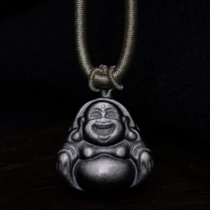Silver sheen obsidian Laughing Buddha pendant front view on wooden background, dark grey obsidian with brown braided necklace cord
