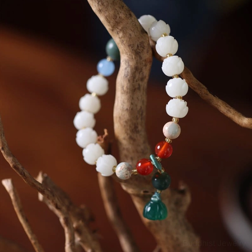 Handmade Buddhist lotus bead bracelet hanging on wooden branch with red agate and jade accents