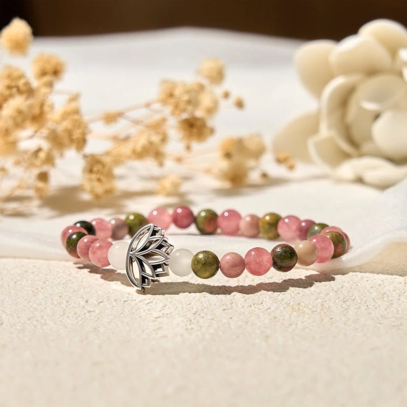 Handcrafted stone bead bracelet with silver lotus charm and natural round beads on white fabric