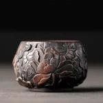 Handcrafted ceramic kung fu tea cup with embossed lotus floral patterns and brown finish, close-up front view