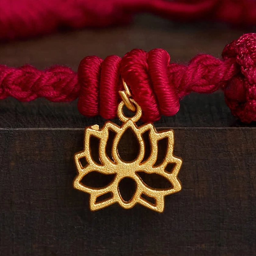 Macro close-up of red lotus bracelet focusing on large gold hollow lotus pendant with intricate carved details