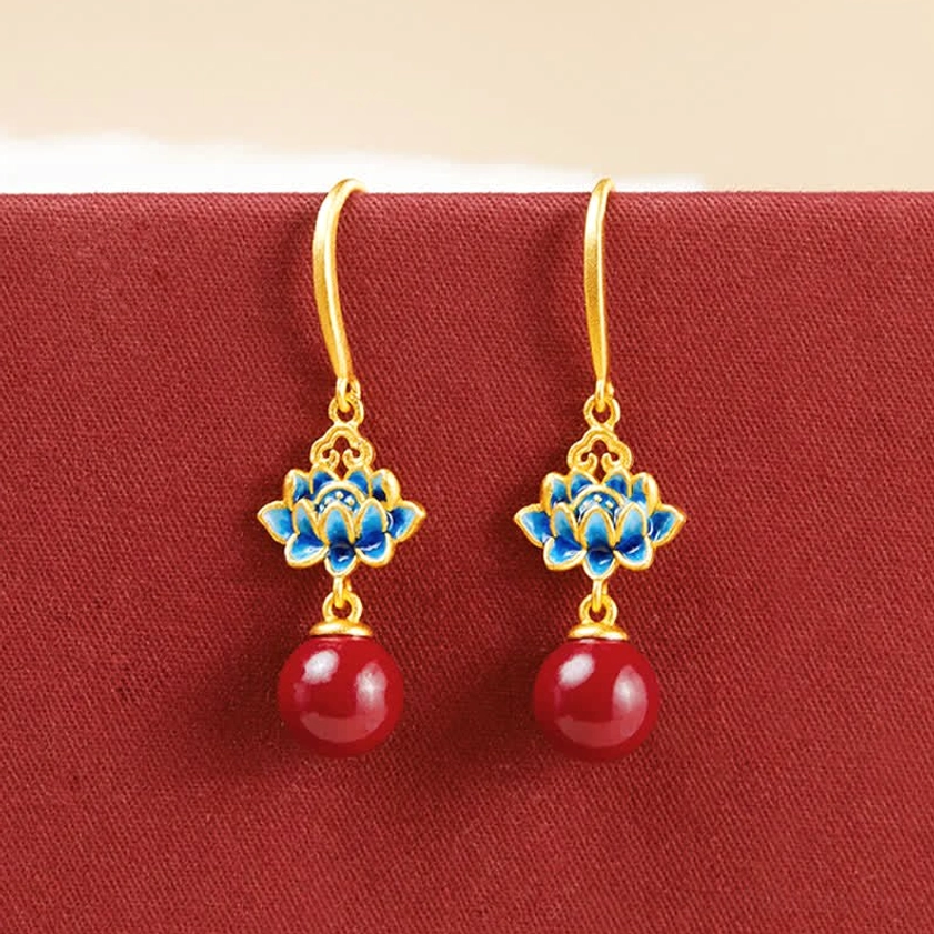 Sterling silver lotus earrings with red cinnabar and blue enamel on red fabric background - front product view