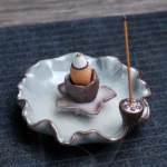 Lotus-themed ceramic backflow incense burner with brown crackle glaze, showing flowing smoke cascade on wooden table