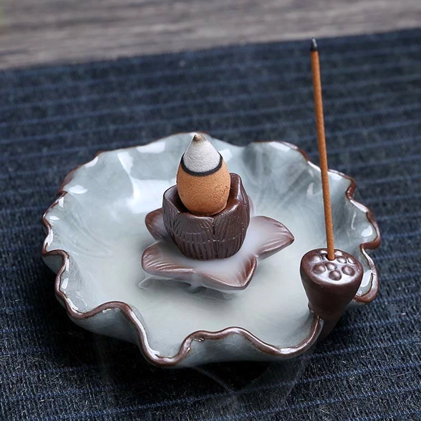 Lotus-themed ceramic backflow incense burner with brown crackle glaze, showing flowing smoke cascade on wooden table