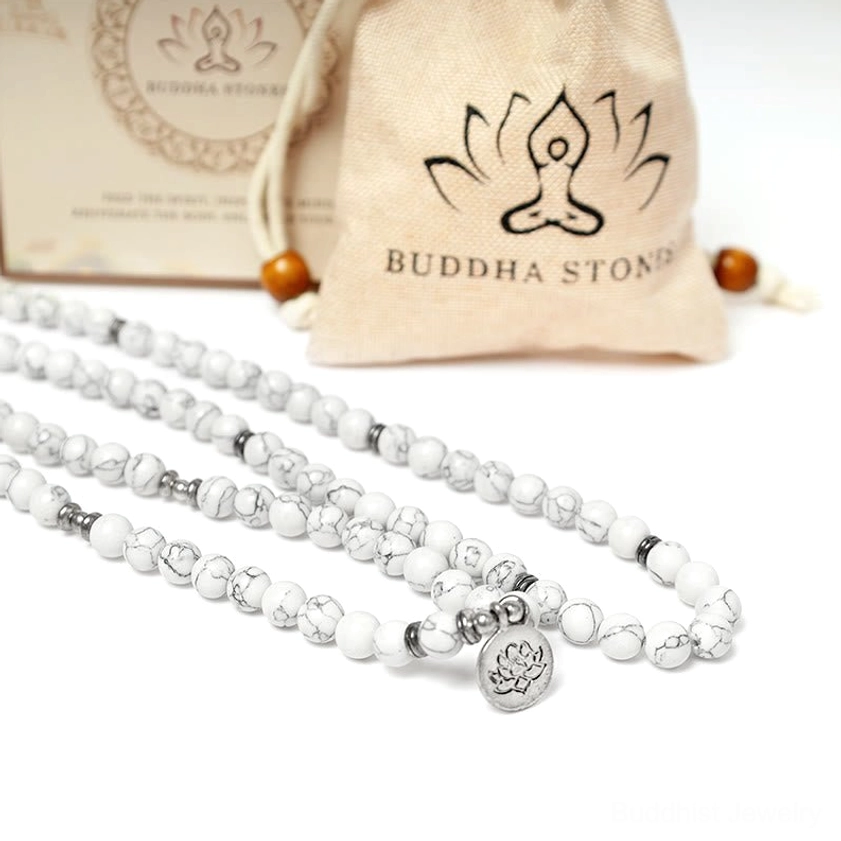 Multiple white turquoise lotus mala bracelets laid out showing smooth natural stone beads silver spacers and lotus charm pendant