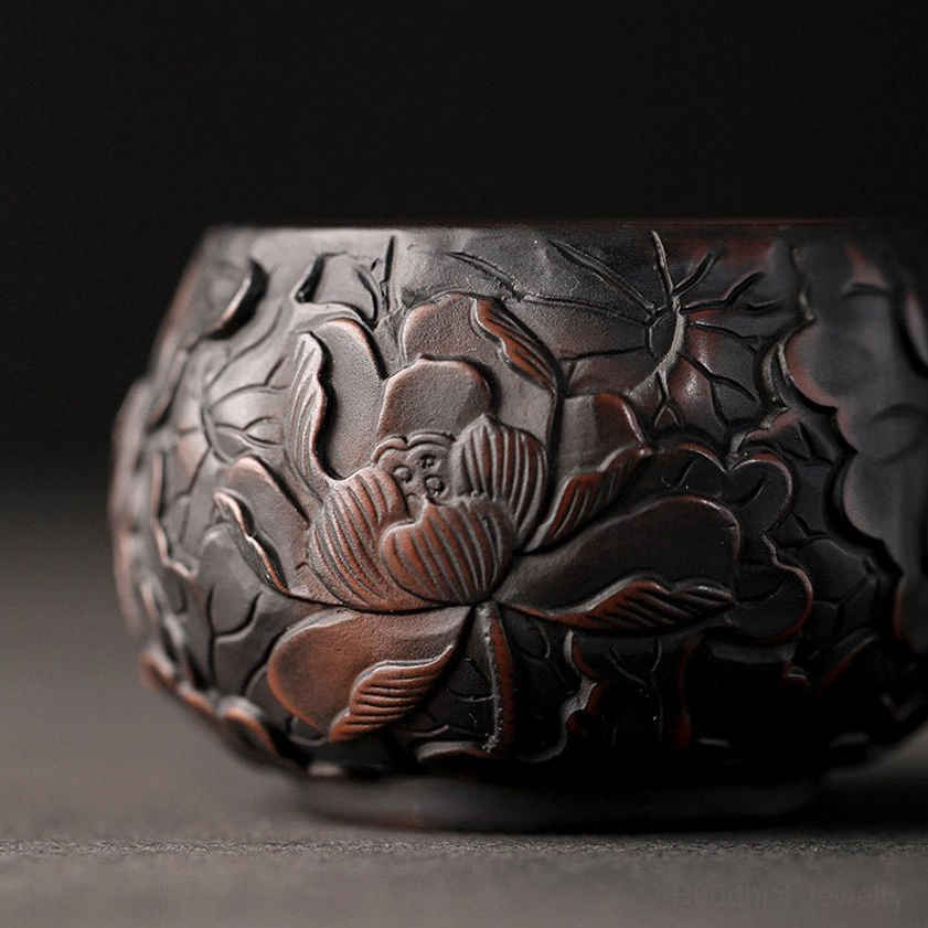 Detailed side close-up of ceramic tea cup showing ultra-detailed embossed lotus motifs with reddish-brown accents
