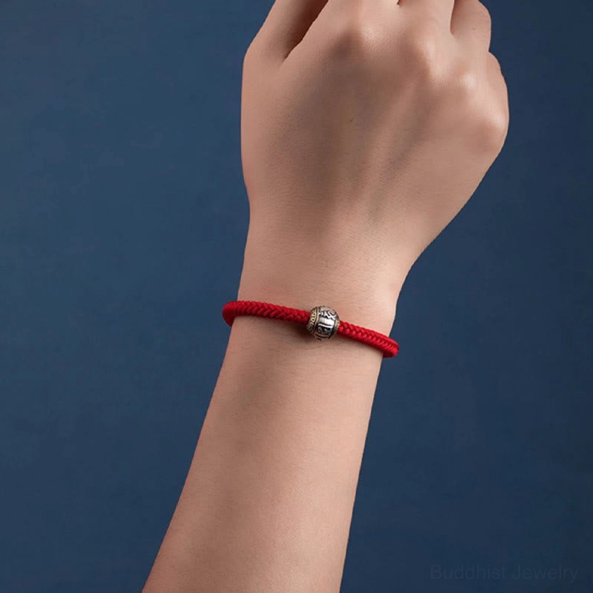 Buddhist luck and protection bracelet with red rope, silver Om Mani Padme Hum mantra bead, and artisanal braided design