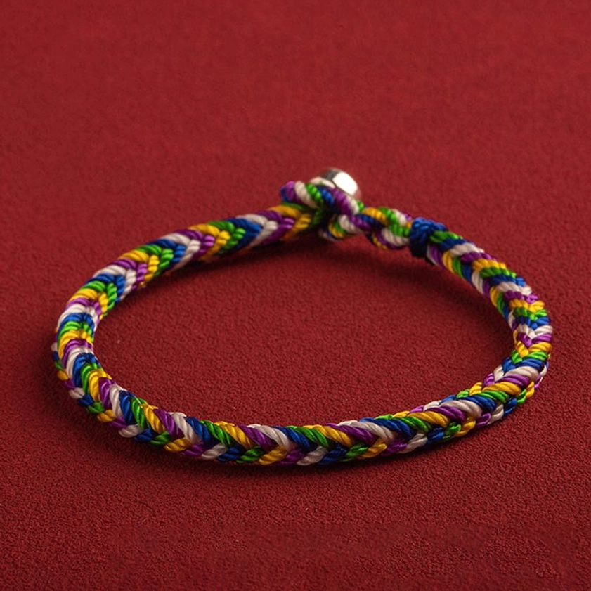 Complete five-color Buddhist lucky bracelet in circular form, top-down flat lay showing full rainbow braided design and silver buckle