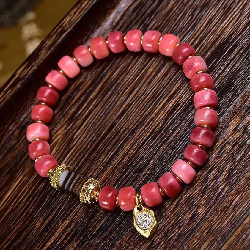 Buddhist lucky bracelet with embossed metal pendant charm and striped dzi bead detail