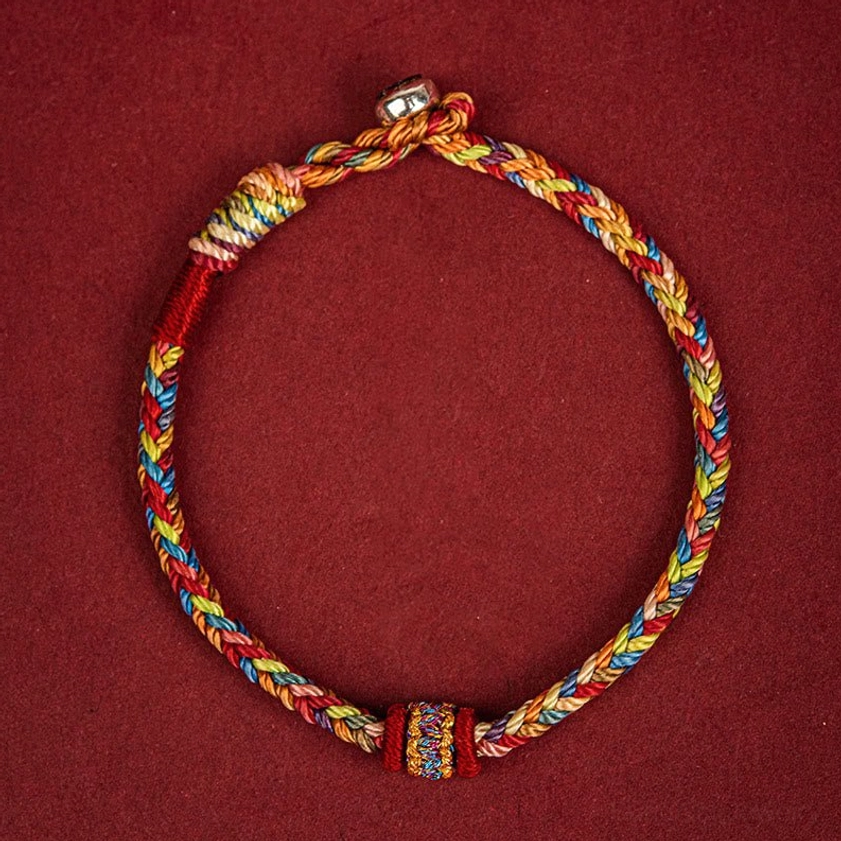 Top-down view of handmade Buddhist string bracelet with central embroidered decoration and adjustable sliding knot closure