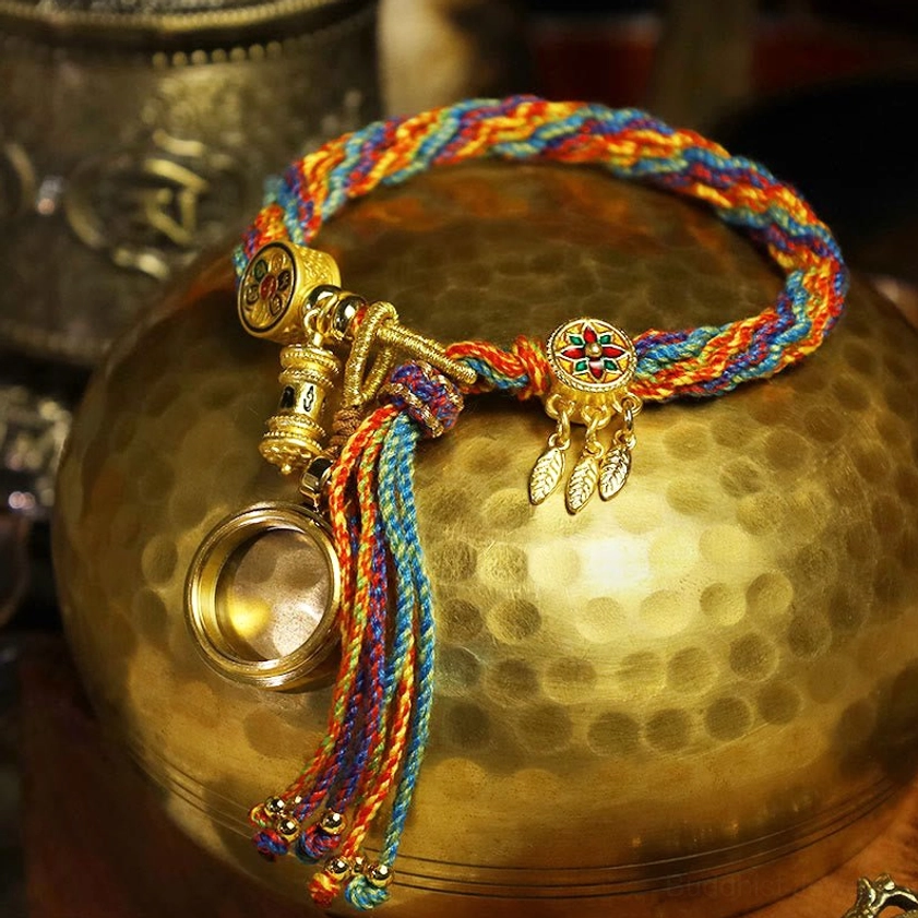 Buddhist string bracelet featuring rainbow braided rope with gold enamel charms and leaf-shaped pendants