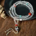 108-bead Buddhist prayer mala with black dzi bead and crystal glass beads displayed on wooden table