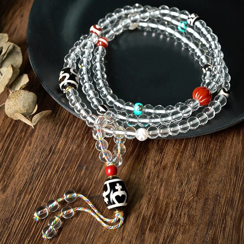 108-bead Buddhist prayer mala with black dzi bead and crystal glass beads displayed on wooden table
