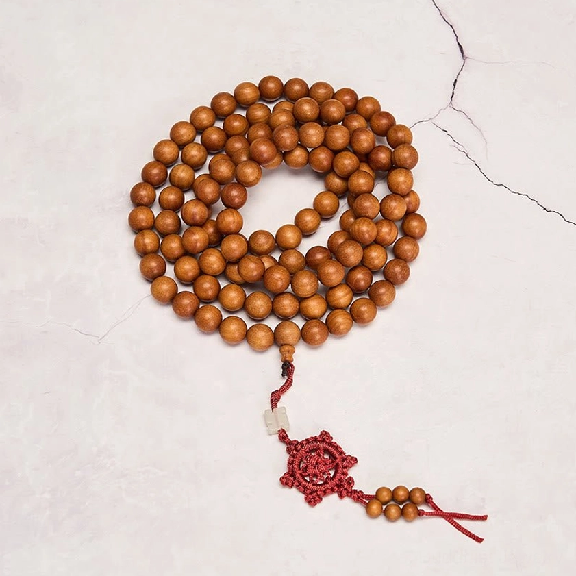 Round 6mm sandalwood prayer mala beads with red Chinese knot on grey cracked background