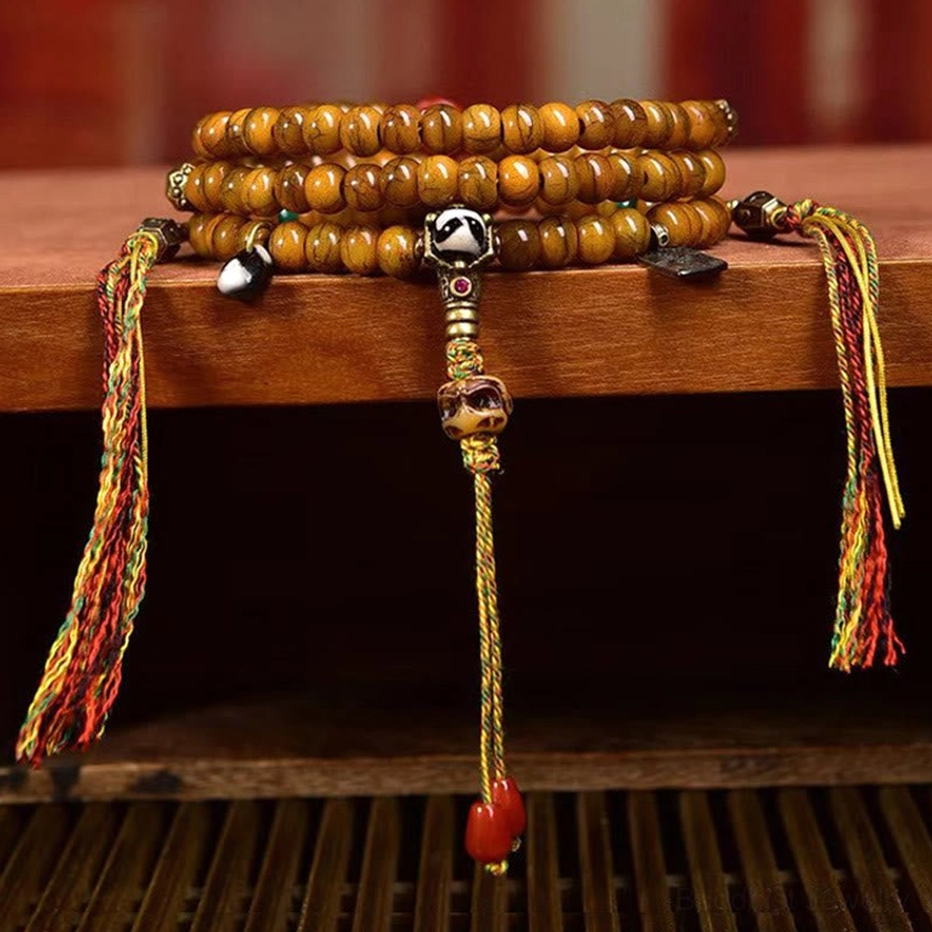 Set of stacked Buddhist prayer malas with uniform tan bone beads, multicolor woven tassels, silver guru bead accents on wooden shelf display