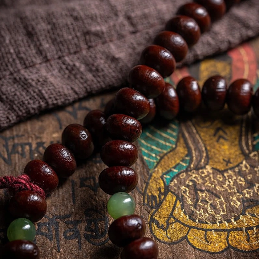 Close-up detailed view of 108 Buddhist mala bead strand showing purple bodhi seeds with green jade spacers
