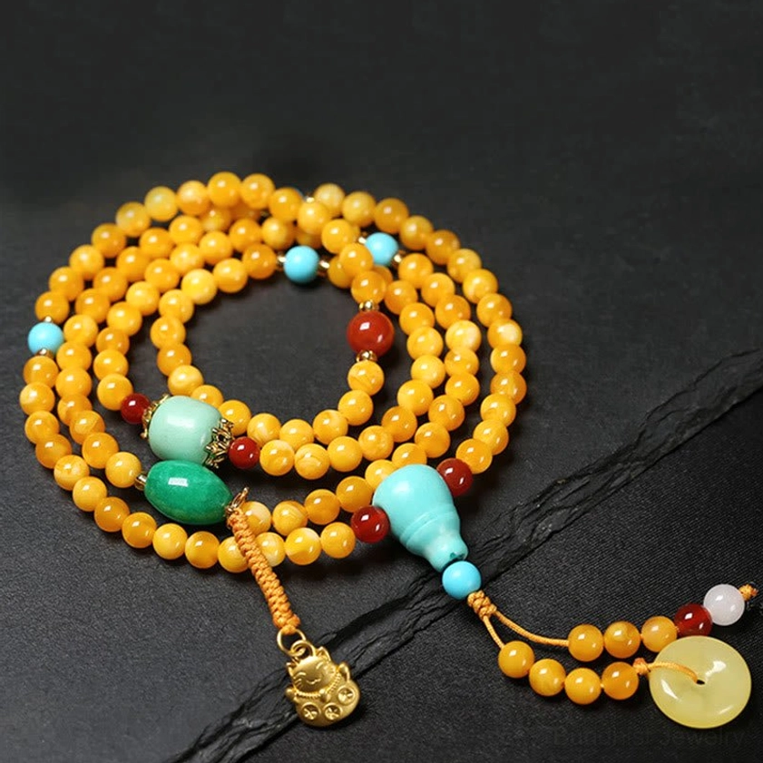 Amber beaded Buddhist prayer mala with turquoise guru bead, red agate, jade peace buckle and gold charm pendant