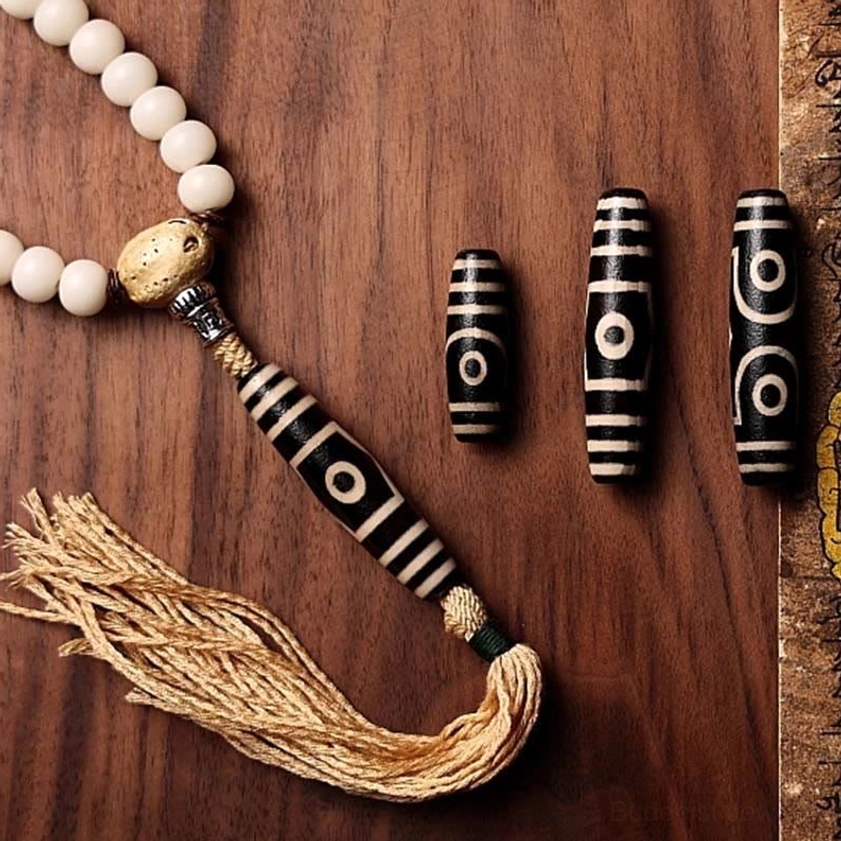 108 bead Buddhist mala with bodhi seed, loose Dzi beads, and cotton tassel pendant on wooden background, prayer necklace detail