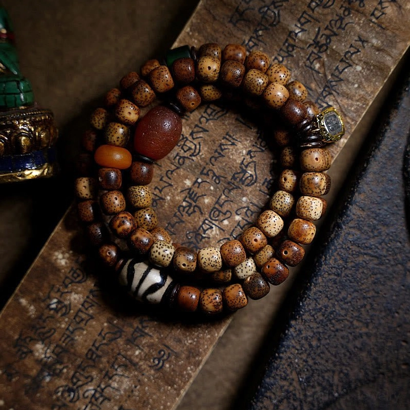 Multi-loop Tibetan prayer bead Buddhist bracelet with bodhi seeds and red agate accent bead on ancient scripture background