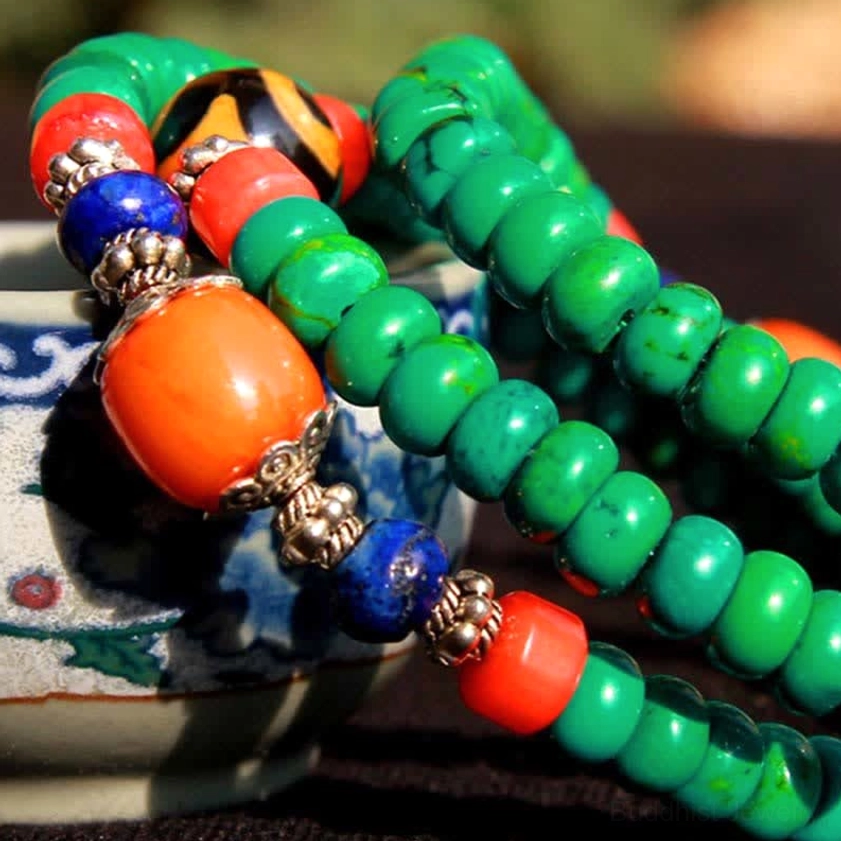 Detailed view of turquoise barrel beads and hand-painted dzi with silver spacers in mala bracelet