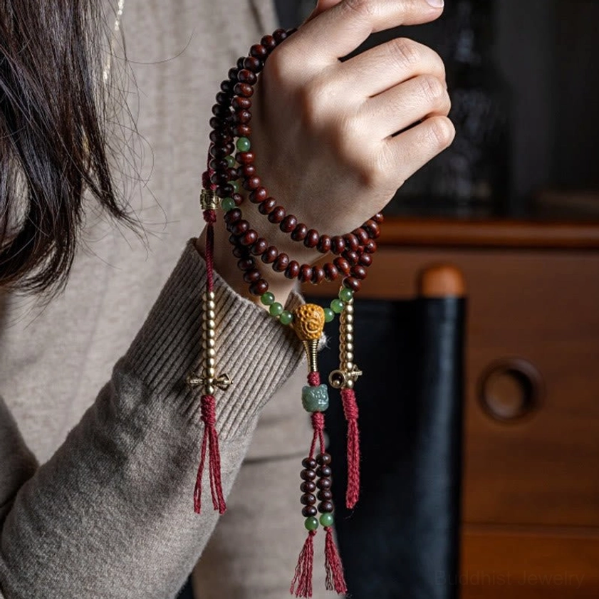 Worn Buddhist prayer mala bracelet on hand showing purple bodhi seeds and jade spacer beads in close-up