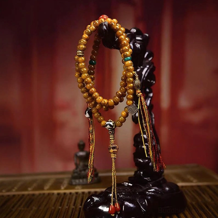 Hanging Buddhist 108-bead prayer mala with Dzi bead focal point, red tassel charm, and silver decorative accents on display stand