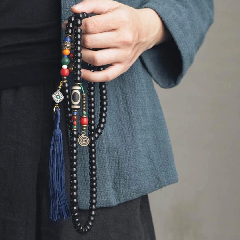 Handmade Buddhist mala bracelet with black ebony wood beads and copper accents - hand held close-up