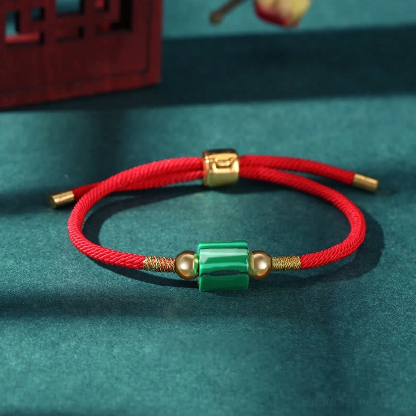 Malachite handmade Buddhist bracelet with red braided rope showing banded pattern and gold hardware