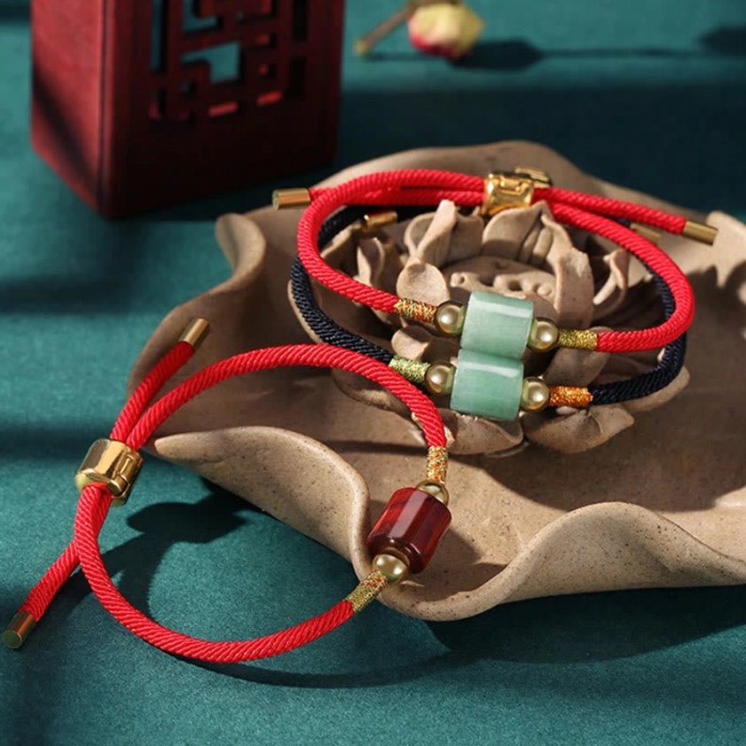 Malachite Buddhist protection bracelet with red braided rope showing natural green stone transformation energy