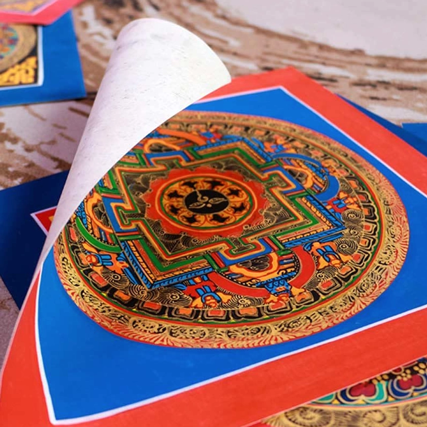 Close-up detail of single handmade Buddhist mandala thangka with intricate deity design and blue-red square border