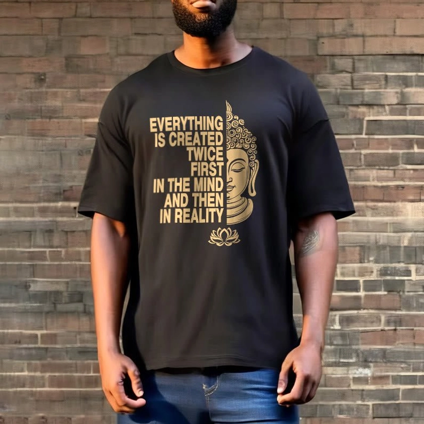 Man modeling black Buddhist graphic tee with blue jeans outdoors against brick wall background