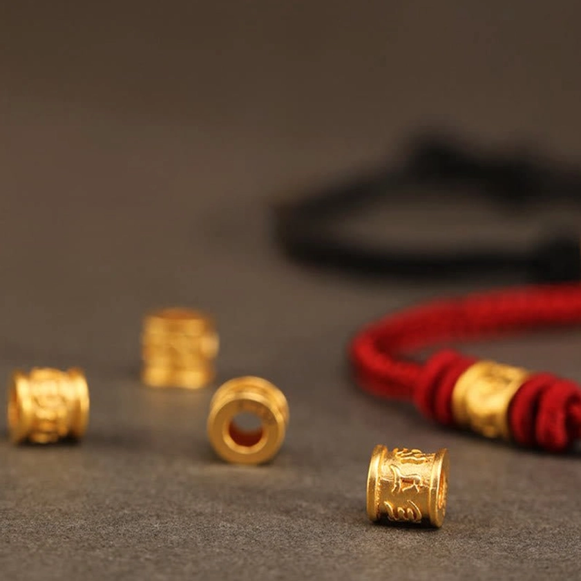 Multiple engraved gold mantra beads and red black braided Buddhist bracelets, product samples
