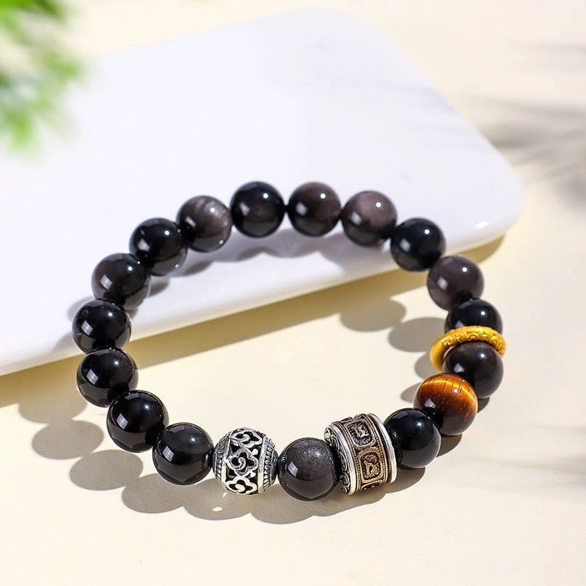 Flat lay overhead view of obsidian tiger eye spiritual bracelet with yellow accents on white ceramic plate