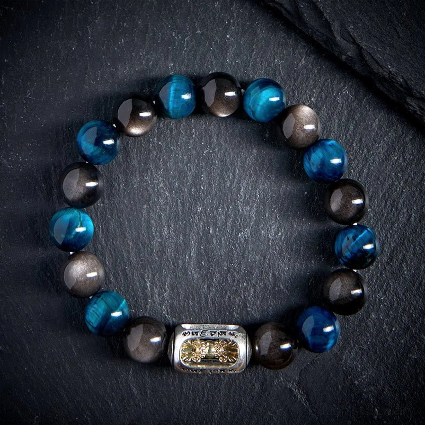 Full circular display of handcrafted Buddhist bracelet showing complete bead arrangement with central engraved metal charm on black fabric