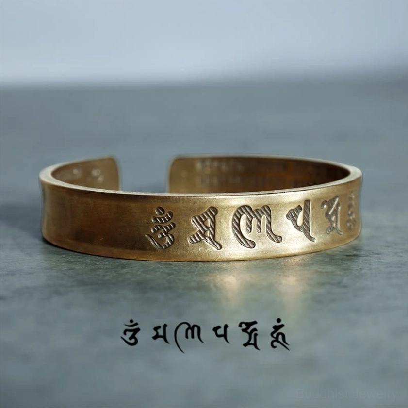 Six-syllable mantra engraved on vintage brass cuff bracelet, side view showing detailed Sanskrit inscription