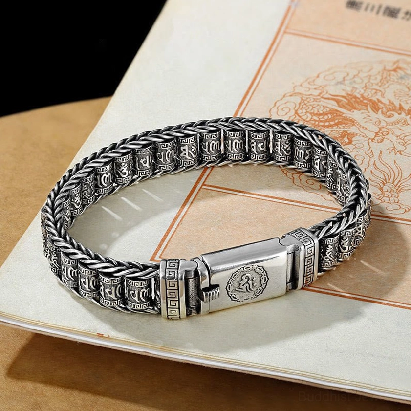 Handcrafted Buddhist mantra copper bracelet laid flat on vintage paper, showing intricate woven chain links and OM symbol clasp
