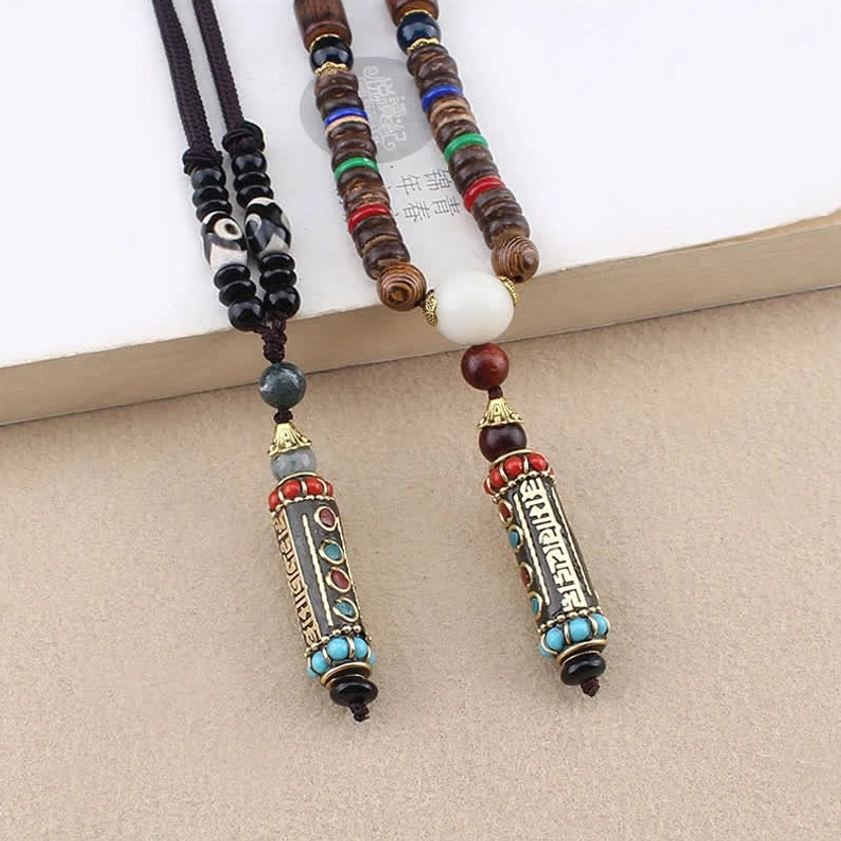 Tibetan Buddhist dzi bead necklace with mantra charm pendant arranged on light desktop, flat lay product photography