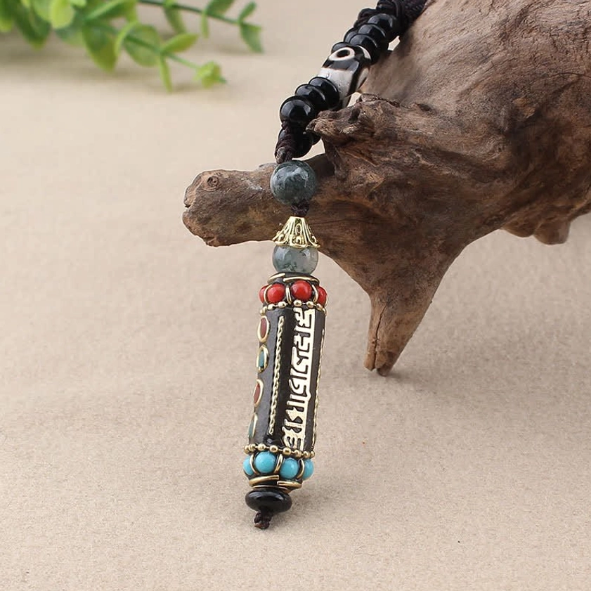Close-up detail of Om Mani Padme Hum Buddhist necklace pendant with dzi bead and wooden ornament accent
