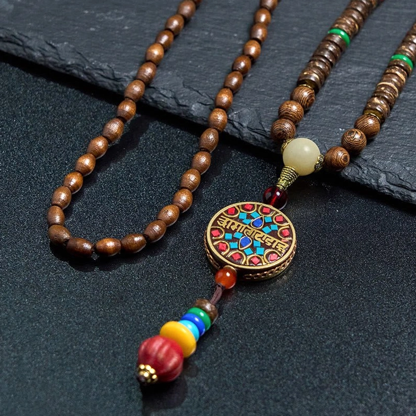 Close-up of Buddhist necklace pendant showing intricate Sanskrit mantra engraving and enamel work